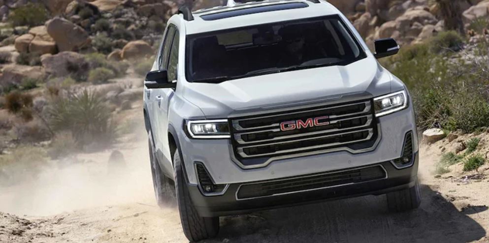 A white 2022 GMC Acadia driving down a rocky surface.