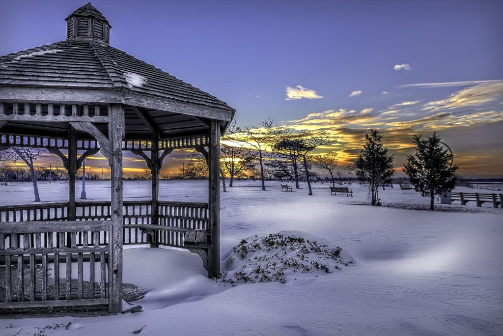 A park gazebo in the winter with snow on the ground on a relatively sunny, clear sky day.