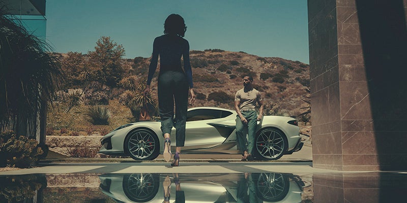 A person walking toward their friend who is leaning against a 2024 Chevy Corvette Z06.