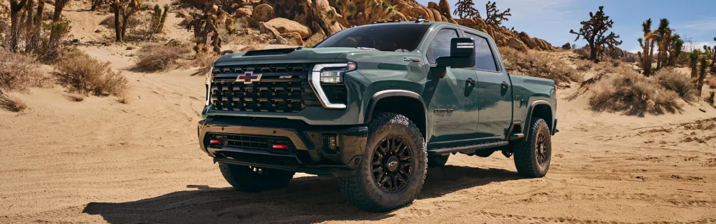 Chevrolet Silverado pickup truck parked on sandy desert terrain with rugged off-road styling.