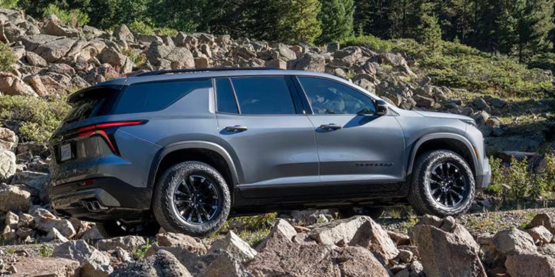 Gray Jeep Wagoneer SUV driving over rocky terrain in an outdoor setting